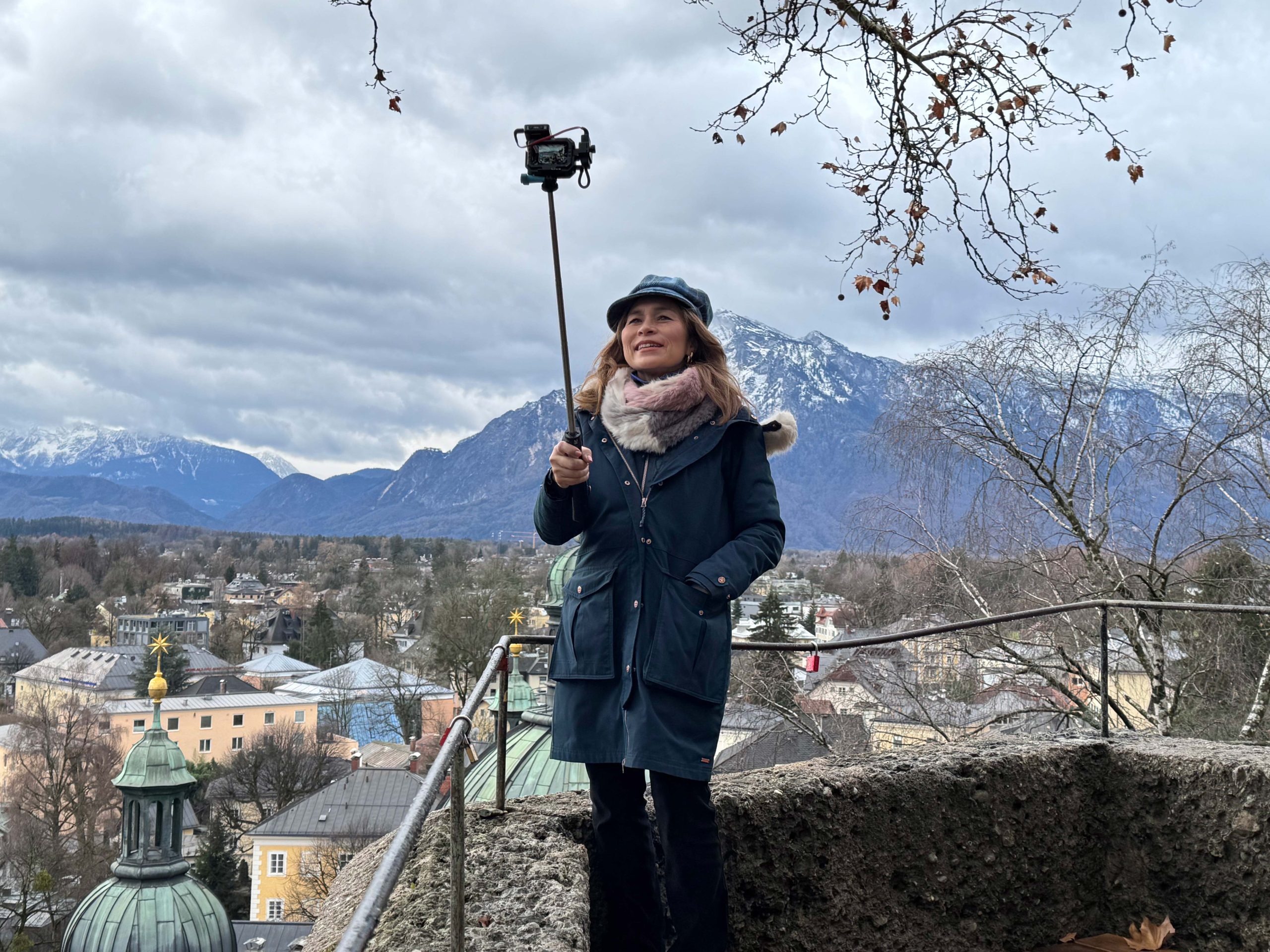 Traveler from Mary-Goes-Round the World overlooking Salzburg with historic rooftops and the Alps in the background.